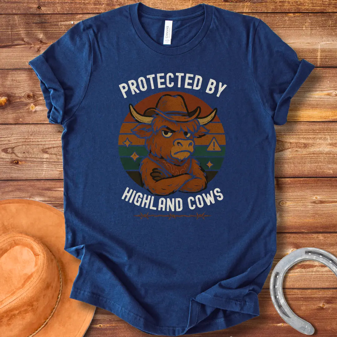 Protected by Highland Cows t-shirt featuring a cartoon Highland cow wearing a cowboy hat with a stern look.