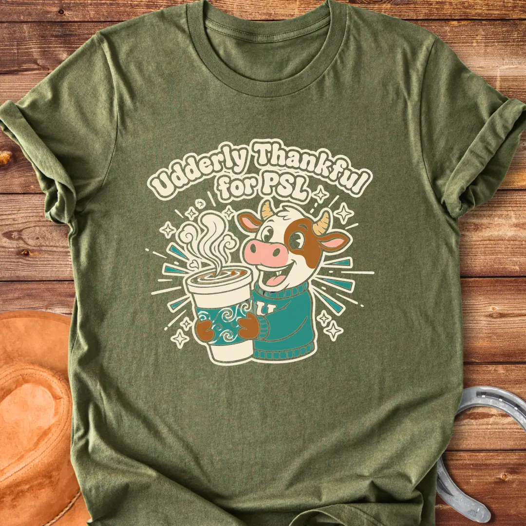 Cartoon cow holding a PSL cup, text reads 'Udderly Thankful for PSL', Cow Lovers Clothing t-shirt design
