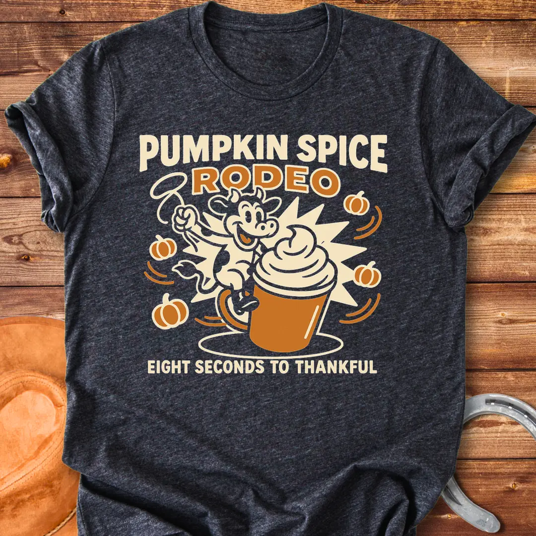 Pumpkin Spice Rodeo T-Shirt featuring a cow riding a pumpkin spice latte, with pumpkins in the background.