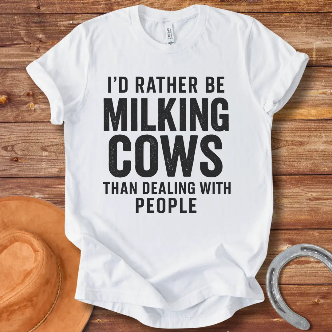 A black and white graphic t-shirt design with the text 'I'd rather be milking cows than dealing with people'.