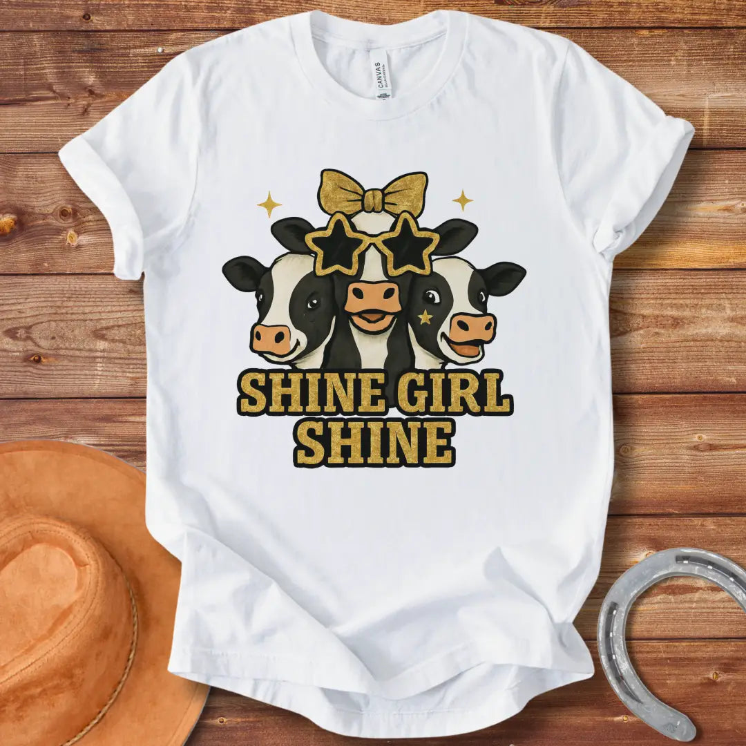 Shine Girl Shine t-shirt featuring three cute cow faces wearing star-shaped sunglasses and gold accents, perfect for cow lovers.