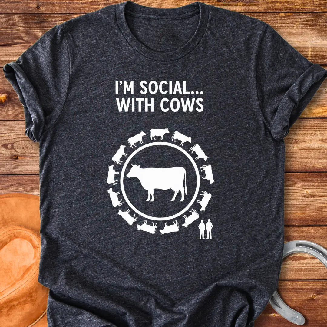 Black and white t-shirt design featuring a cow surrounded by smaller cow silhouettes with the words 'I'm social... with cows' above.