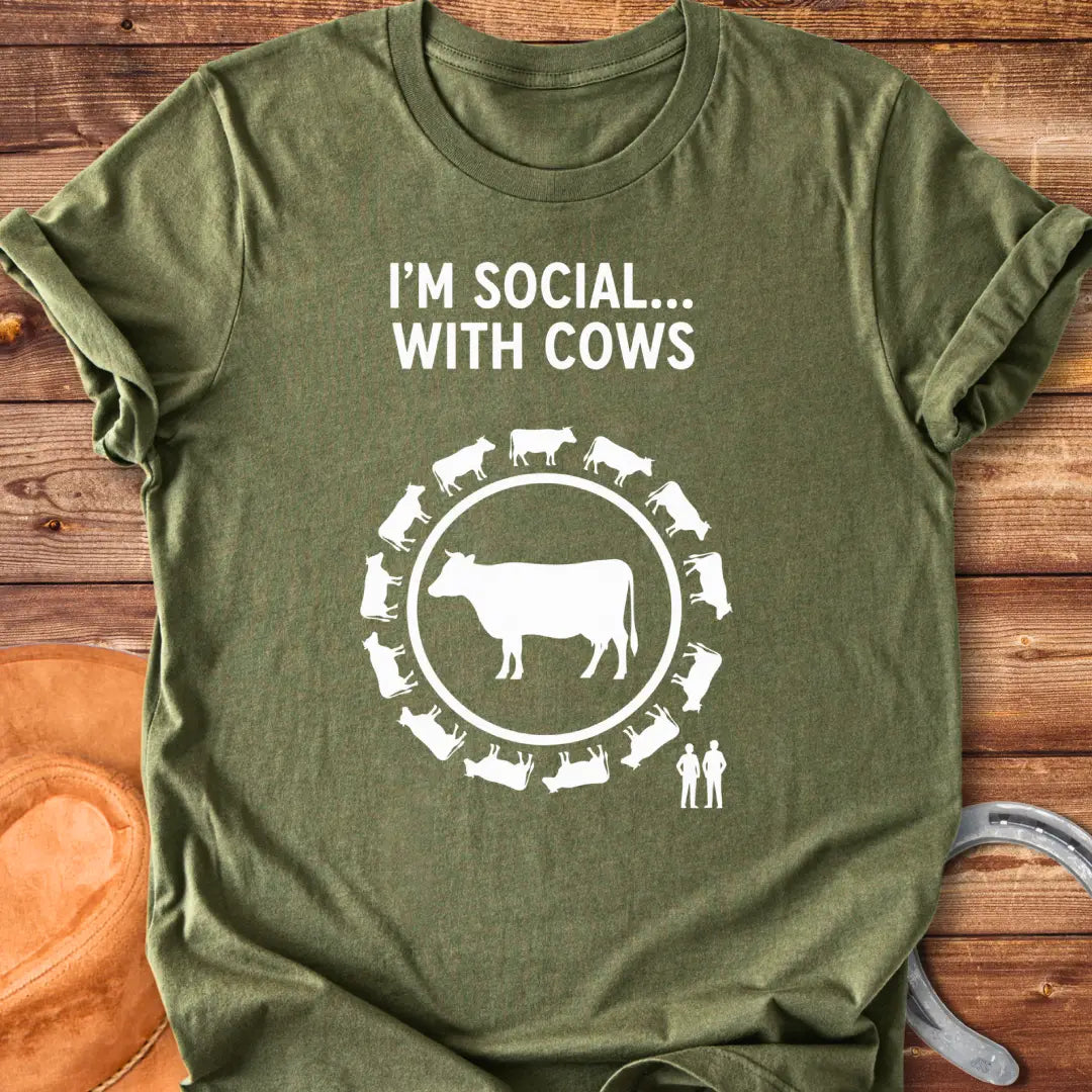 Black and white t-shirt design featuring a cow surrounded by smaller cow silhouettes with the words 'I'm social... with cows' above.