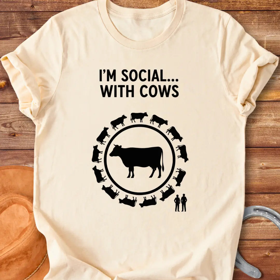 Black and white t-shirt design featuring a cow surrounded by smaller cow silhouettes with the words 'I'm social... with cows' above.