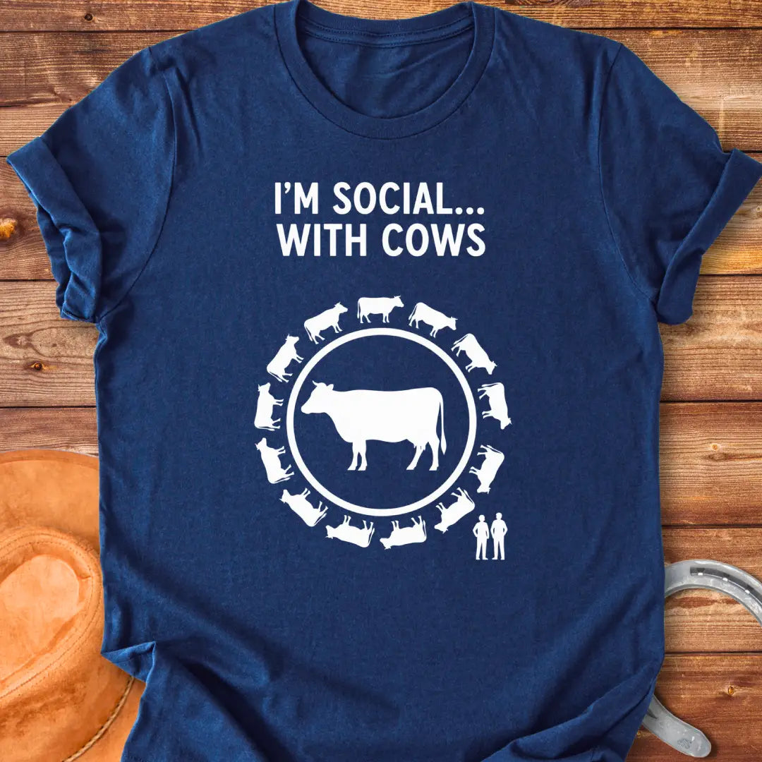 Black and white t-shirt design featuring a cow surrounded by smaller cow silhouettes with the words 'I'm social... with cows' above.
