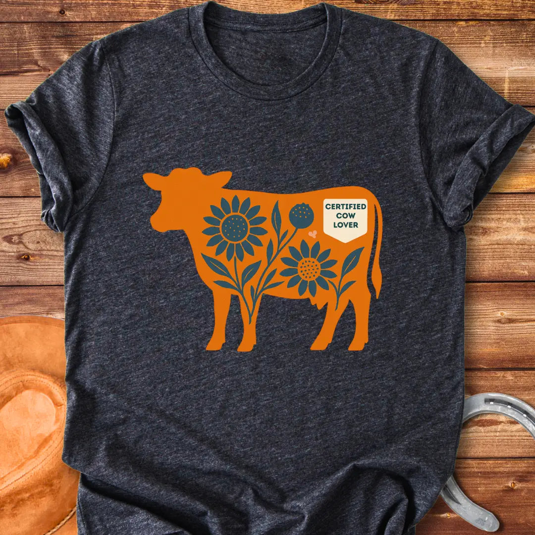 Sunflower Stockyard T-Shirt featuring an orange cow silhouette filled with blue sunflowers, a floral design, and a Certified Cow Lover badge.