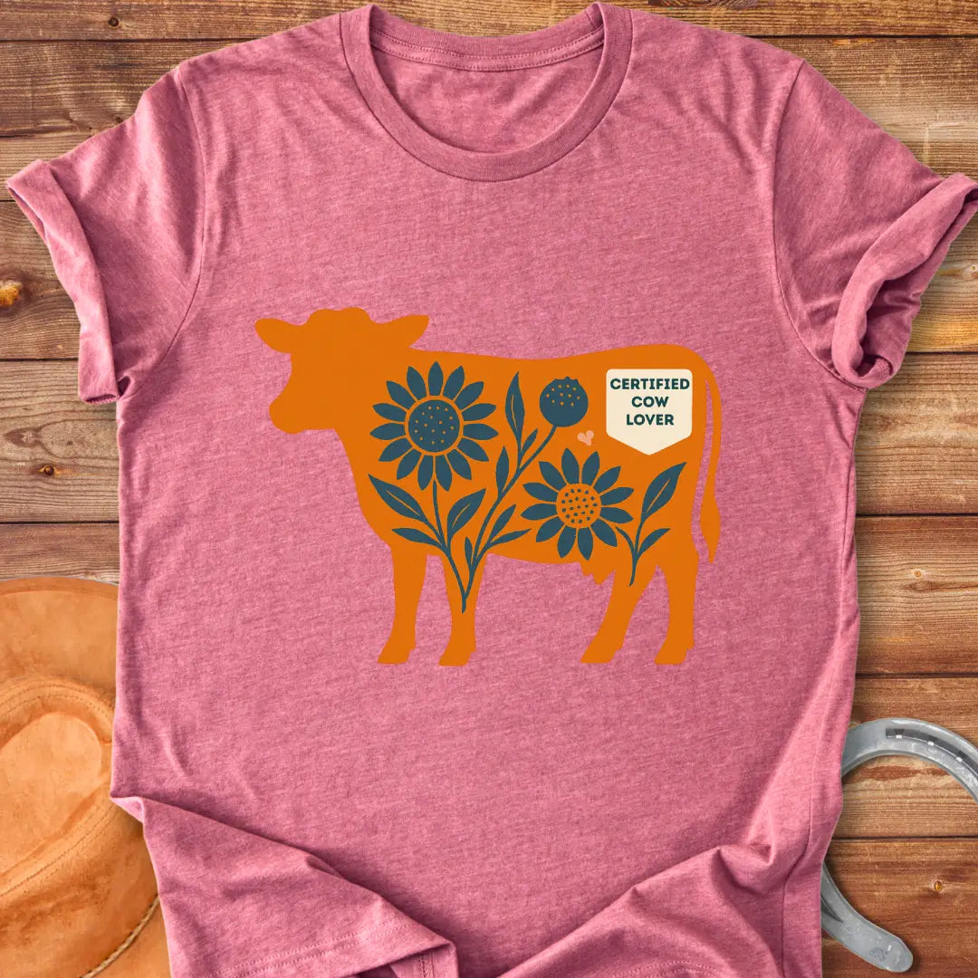 Sunflower Stockyard T-Shirt featuring an orange cow silhouette filled with blue sunflowers, a floral design, and a Certified Cow Lover badge.