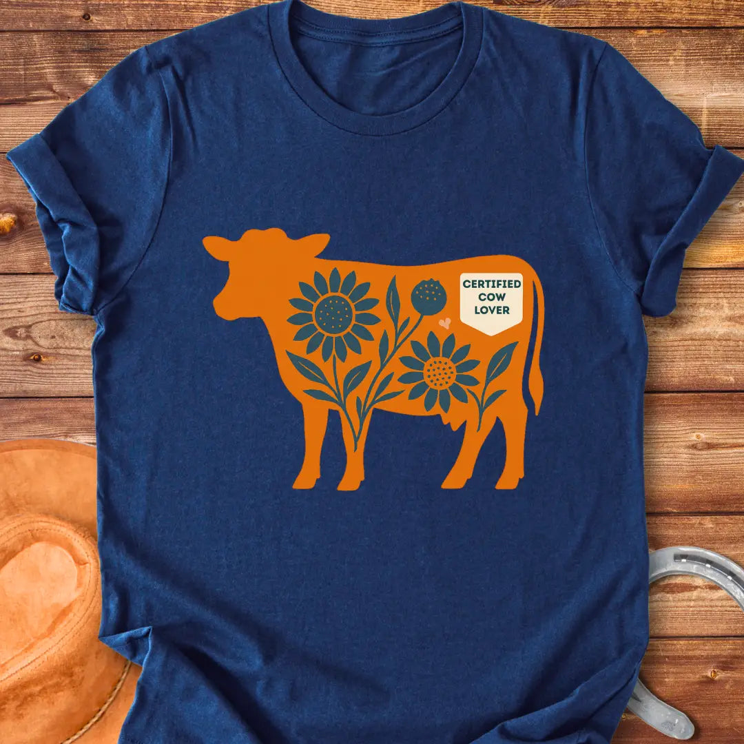 Sunflower Stockyard T-Shirt featuring an orange cow silhouette filled with blue sunflowers, a floral design, and a Certified Cow Lover badge.