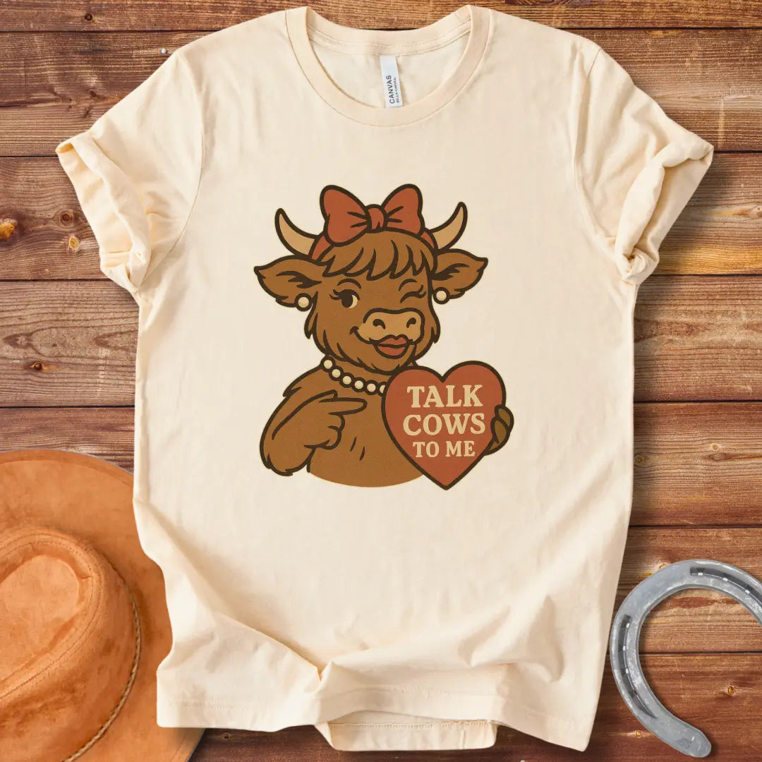 Charming cow wearing a bow and pearl necklace, holding a heart-shaped sign that says 'Talk Cows To Me'