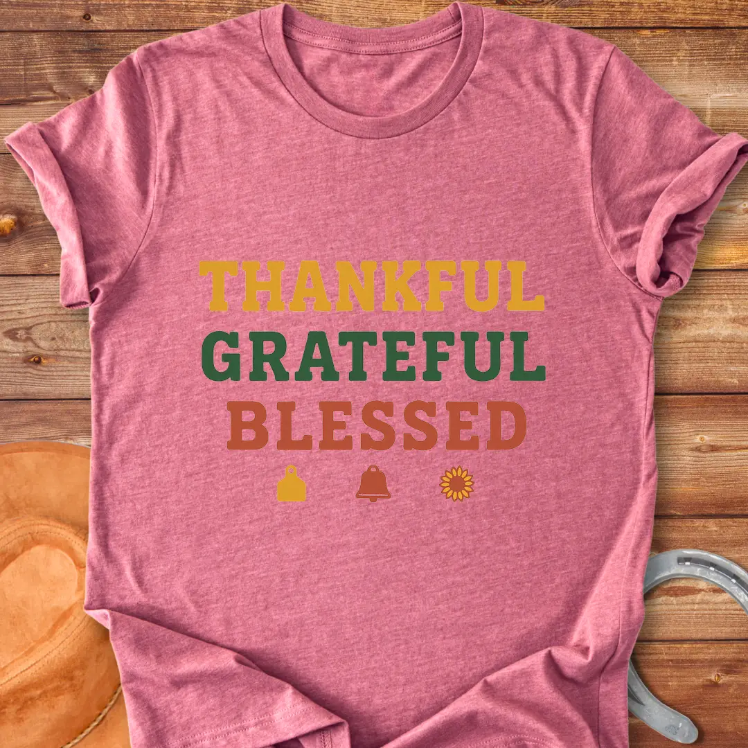 Thankful, Grateful, Blessed T-shirt with farm-themed elements like a cow tag, bell, and sunflower.