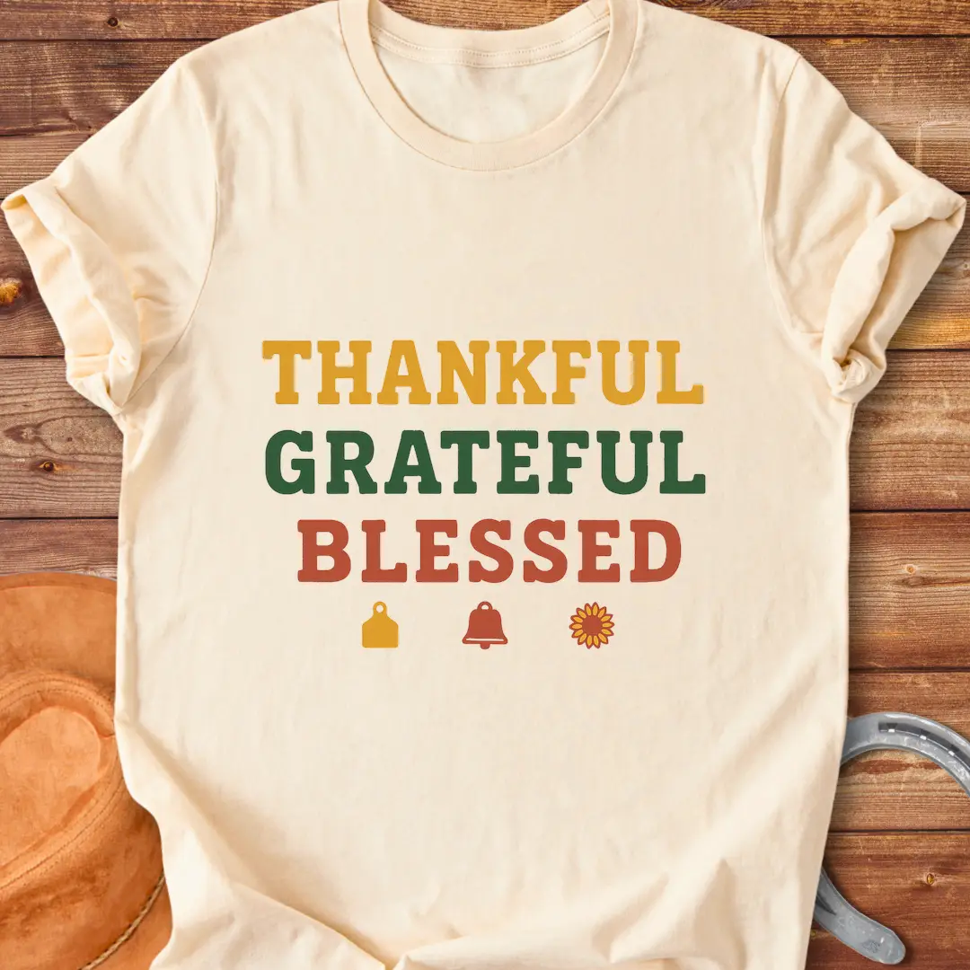 Thankful, Grateful, Blessed T-shirt with farm-themed elements like a cow tag, bell, and sunflower.