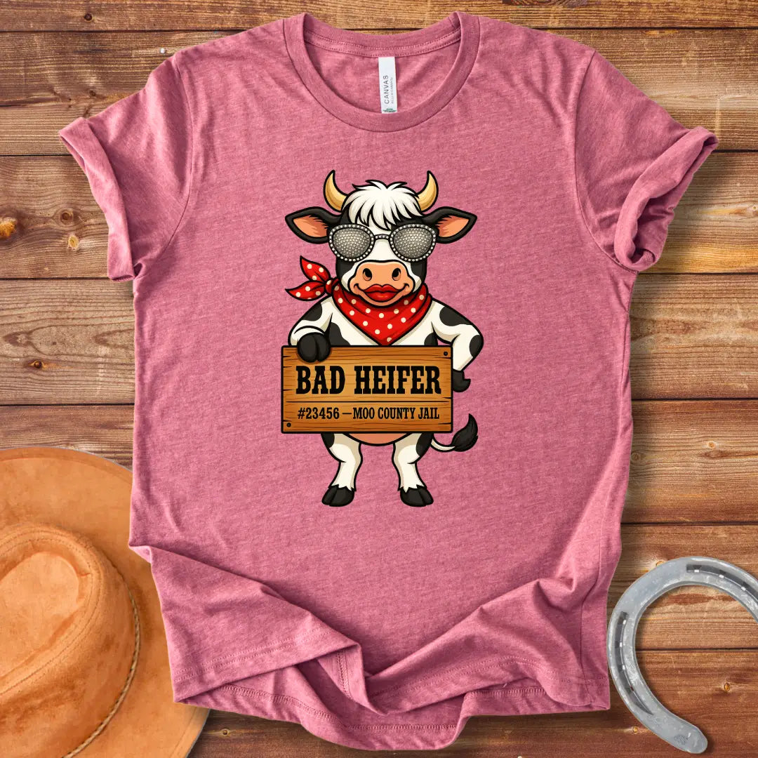 Cartoon cow wearing sunglasses and bandana, holding a sign that says 'Bad Heifer'.