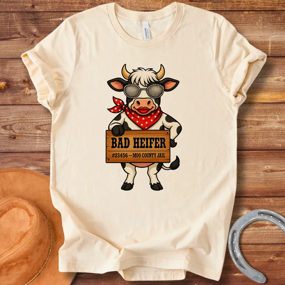 Cartoon cow wearing sunglasses and bandana, holding a sign that says 'Bad Heifer'.