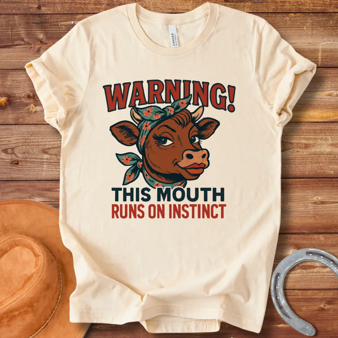 Illustration of a cow with a bandana and the words 'Warning! This Mouth Runs On Instinct' on a black background.