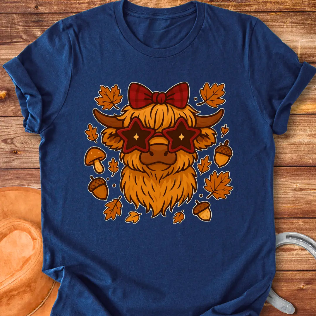 Cartoon illustration of a Highland cow wearing star-shaped sunglasses and a bow, surrounded by acorns, mushrooms, and fall leaves.