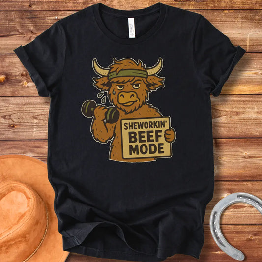 Cartoon cow working out with dumbbells, wearing a headband and holding a sign that says 'Sheworkin' Beef Mode'