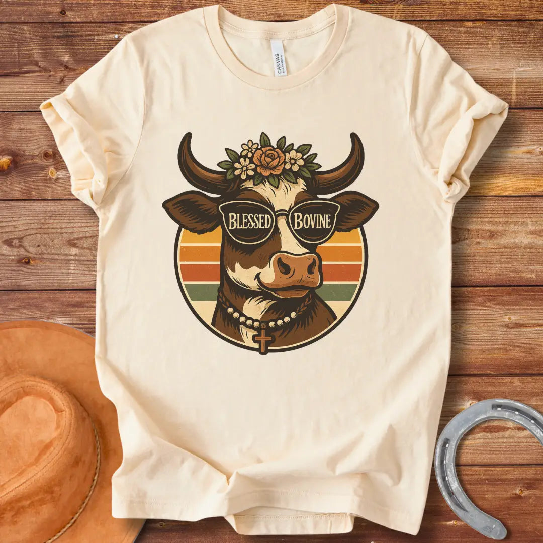 Blessed Bovine T-shirt design featuring a cow wearing sunglasses that say blessed bovine with a floral crown and a rosary.