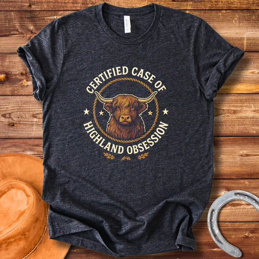 Certified Case of Highland Obsession T-Shirt featuring a detailed illustration of a Highland cow within a rope circle.