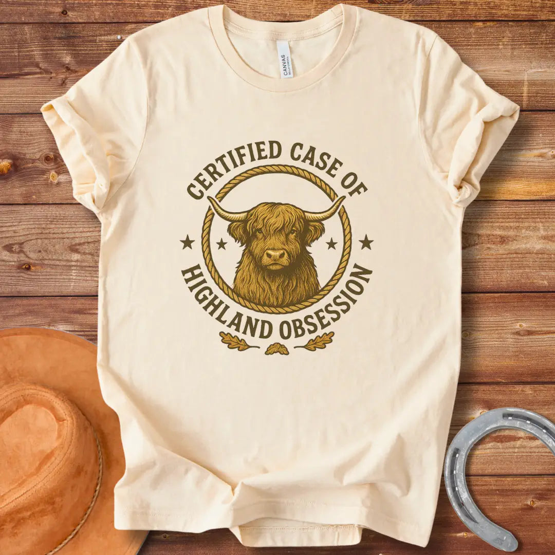 Certified Case of Highland Obsession T-Shirt featuring a detailed illustration of a Highland cow within a rope circle.