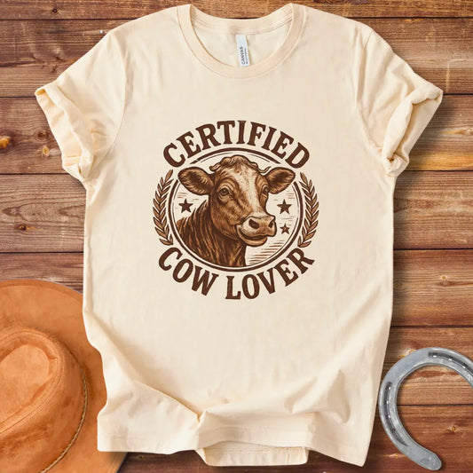 Certified Cow Lover T-shirt featuring a detailed illustration of a cow's face within a circular emblem with the text 'Certified Cow Lover'.