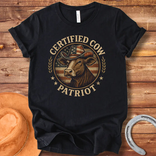 Certified Cow Patriot T-Shirt featuring a cow wearing an American flag cowboy hat, surrounded by stars and wheat stalks.