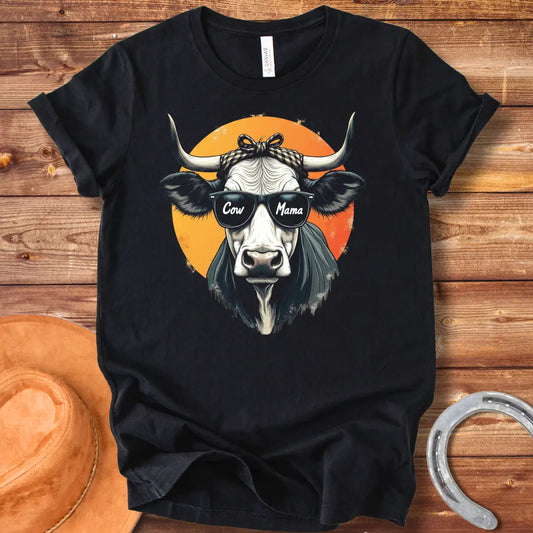Cow Mama T-Shirt featuring a cool cow wearing sunglasses that say 'Cow Mama', against an orange sun.