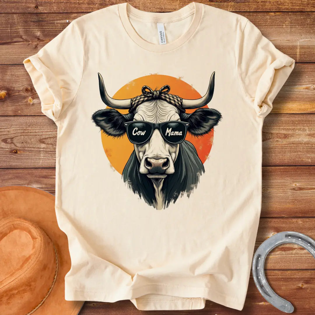 Cow Mama T-Shirt featuring a cool cow wearing sunglasses that say 'Cow Mama', against an orange sun.