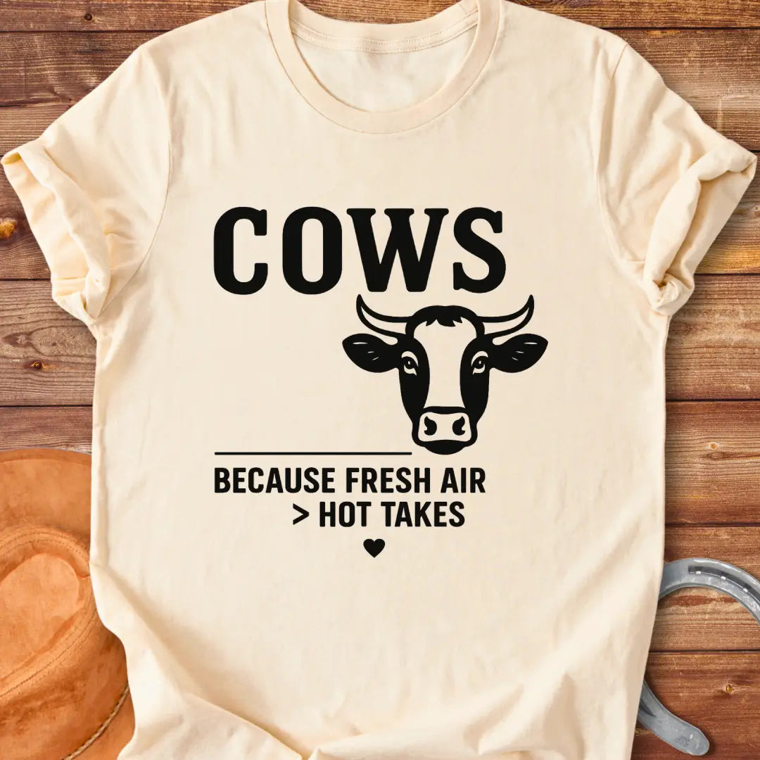 Black and white t-shirt with a cow graphic and the text 'Cows Because Fresh Air Better Than Hot Takes.'