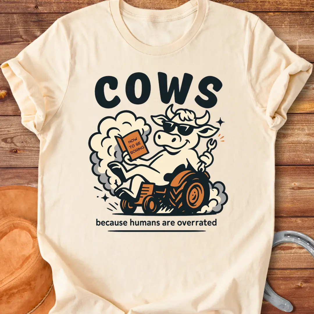 Funny t-shirt design featuring a cool cow reading a book on a tractor with the phrase 'Cows Because Humans Overrated'
