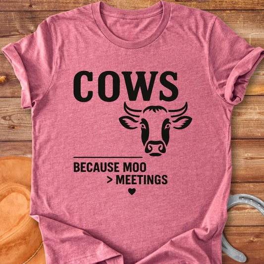 Black and white t-shirt design featuring a cow's face with the words Cows Because Moo Better Than Meetings