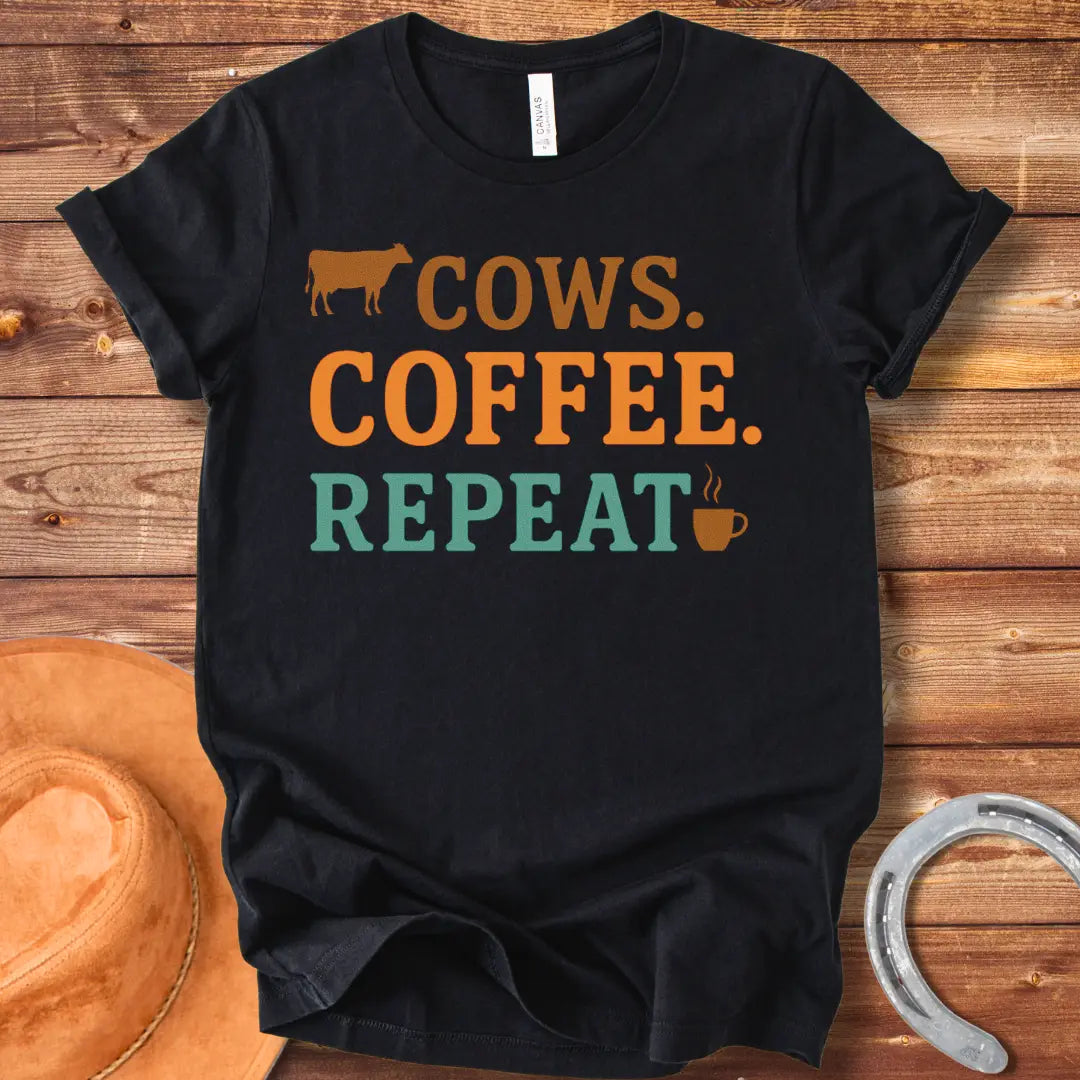 Graphic design on a t-shirt showing a cow silhouette followed by the words 'COWS. COFFEE. REPEAT.' and a coffee cup icon.
