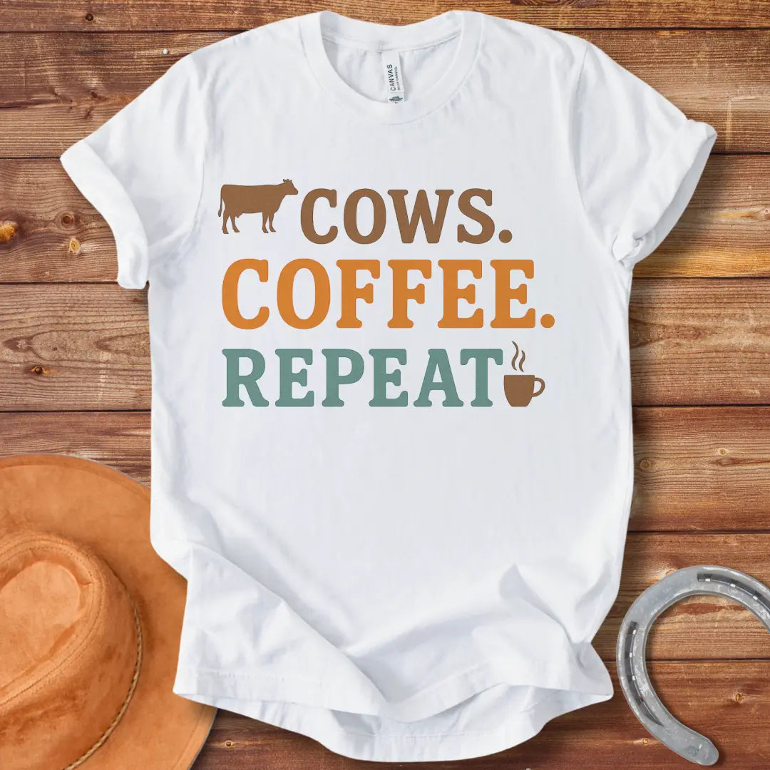 Graphic design on a t-shirt showing a cow silhouette followed by the words 'COWS. COFFEE. REPEAT.' and a coffee cup icon.