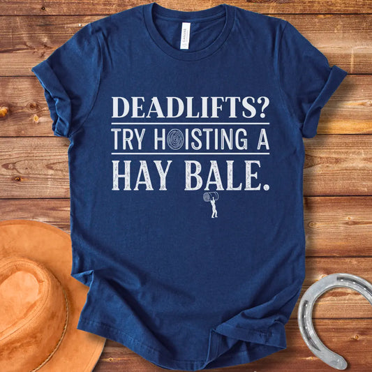 Black and white distressed text graphic on a black t-shirt that reads: 'Deadlifts? Try hoisting a Hay Bale!' with a small barbell graphic at the bottom.