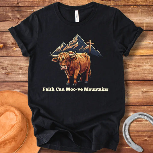 Highland cow graphic t-shirt with the words 'Faith Can Moo-ve Mountains', with mountain range and cross in the background