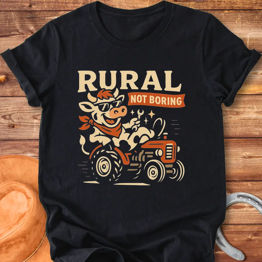Funny t-shirt featuring a cow driving a tractor and the words 'Rural Not Boring'.