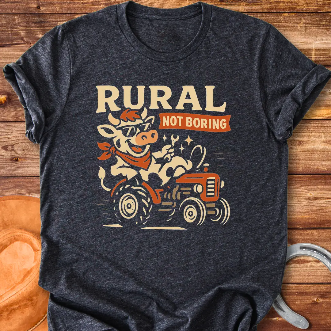 Funny t-shirt featuring a cow driving a tractor and the words 'Rural Not Boring'.