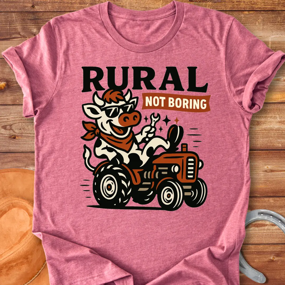 Funny t-shirt featuring a cow driving a tractor and the words 'Rural Not Boring'.