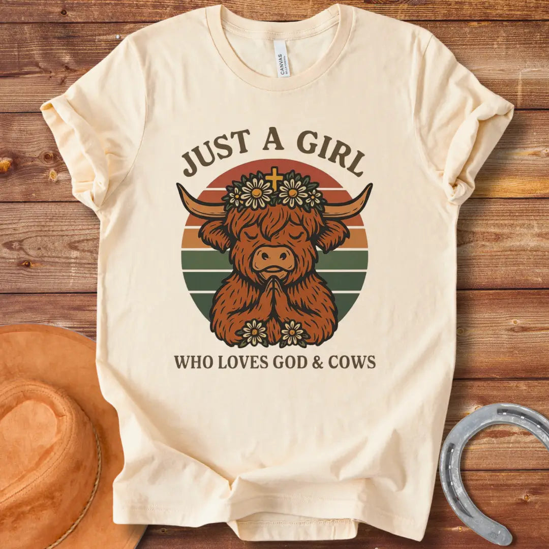 A praying Highland cow wearing a daisy crown with a cross, set against a retro sunset graphic. Text reads: 'Just a girl who loves God & Cows'.