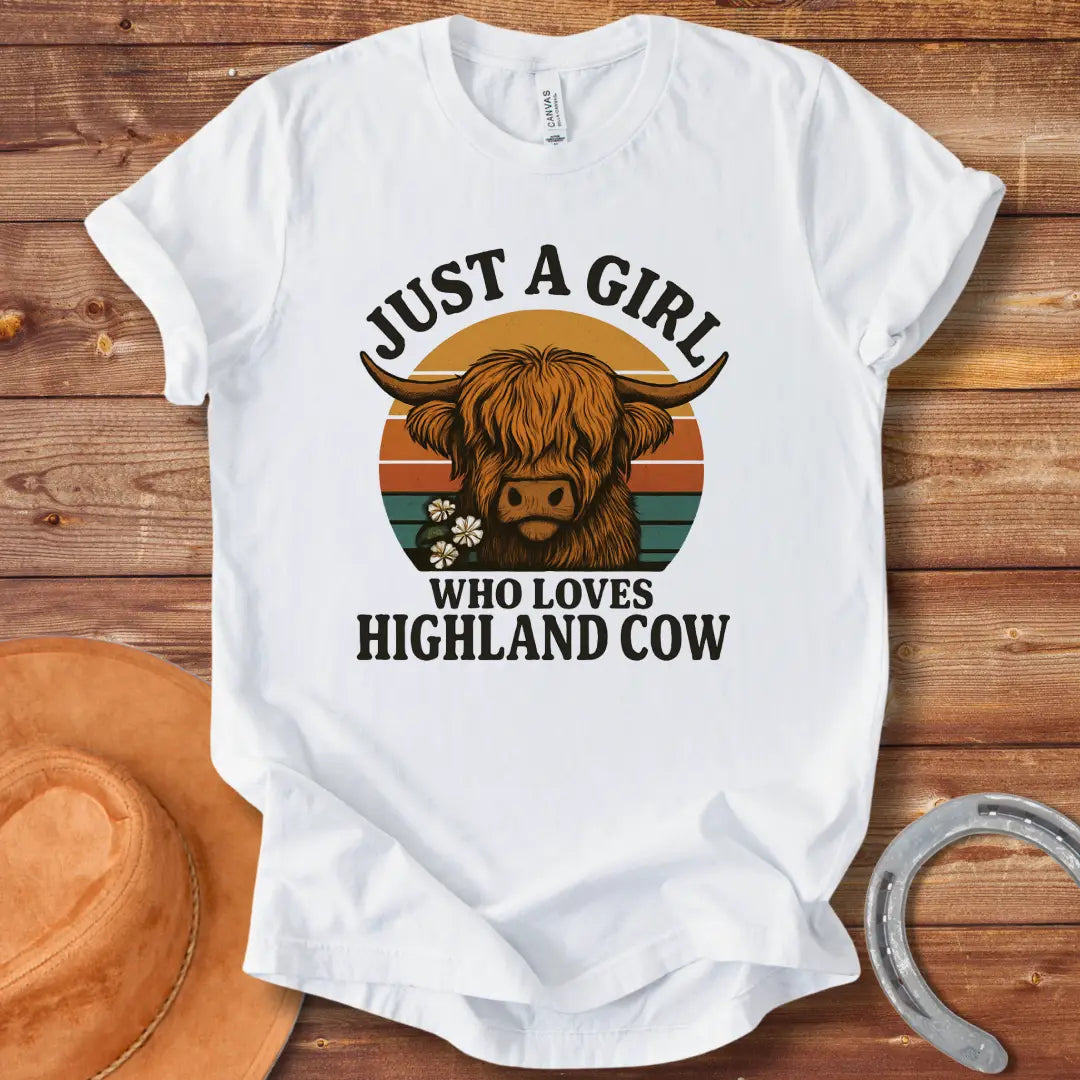 Vintage t-shirt featuring a Highland cow with flowers and the text 'Just a Girl Who Loves Highland Cow' against a retro sunset backdrop.