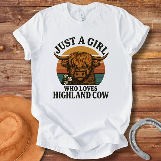 Vintage t-shirt featuring a Highland cow with flowers and the text 'Just a Girl Who Loves Highland Cow' against a retro sunset backdrop.