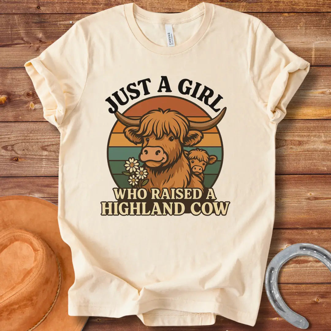 T-shirt design featuring a Highland cow with her calf, the words 'Just a girl who raised a highland cow', and daisies on a vintage sunset background.