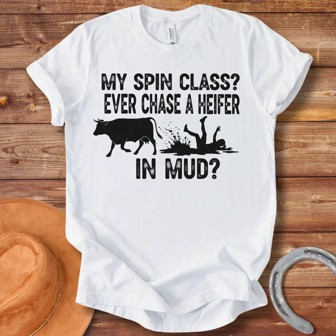 A funny illustration of a cow and a person falling in mud, with the text 'My spin class? Ever chase a heifer in mud?'