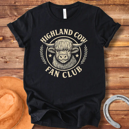 Highland Cow Fan Club T-Shirt featuring a smiling Highland cow in a circular design with text.