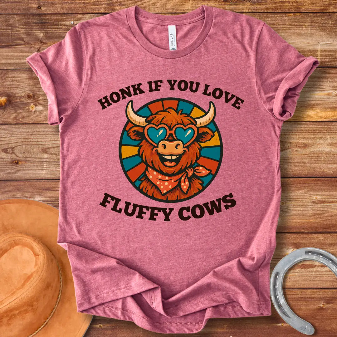 T-shirt design with a smiling cow wearing heart-shaped sunglasses and a bandana, with the text 'Honk If You Love Fluffy Cows'.