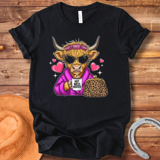 Cartoon image of a cow wearing sunglasses and a robe, holding a mug that says 'Hot Mess Heifer', with a leopard print purse and heart illustrations. 