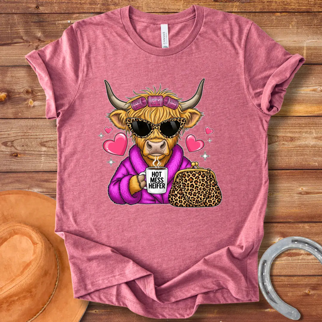 Cartoon image of a cow wearing sunglasses and a robe, holding a mug that says 'Hot Mess Heifer', with a leopard print purse and heart illustrations. 