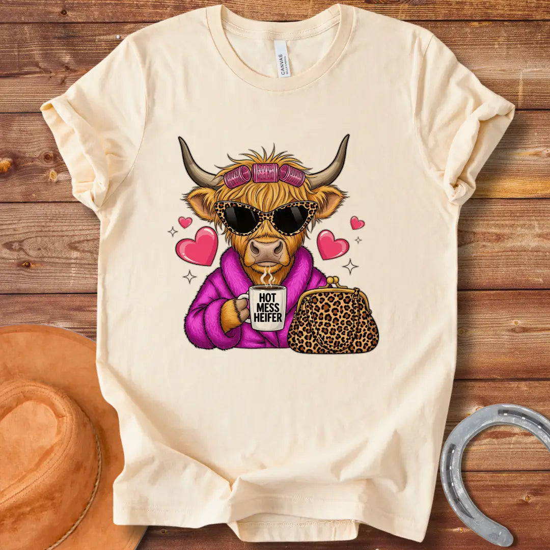 Cartoon image of a cow wearing sunglasses and a robe, holding a mug that says 'Hot Mess Heifer', with a leopard print purse and heart illustrations. 