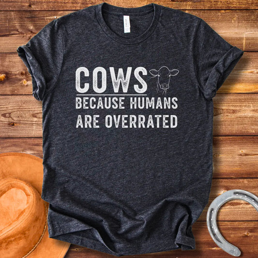 A black and white graphic t-shirt design that reads 'COWS BECAUSE HUMANS ARE OVERRATED' with a simple cow illustration.