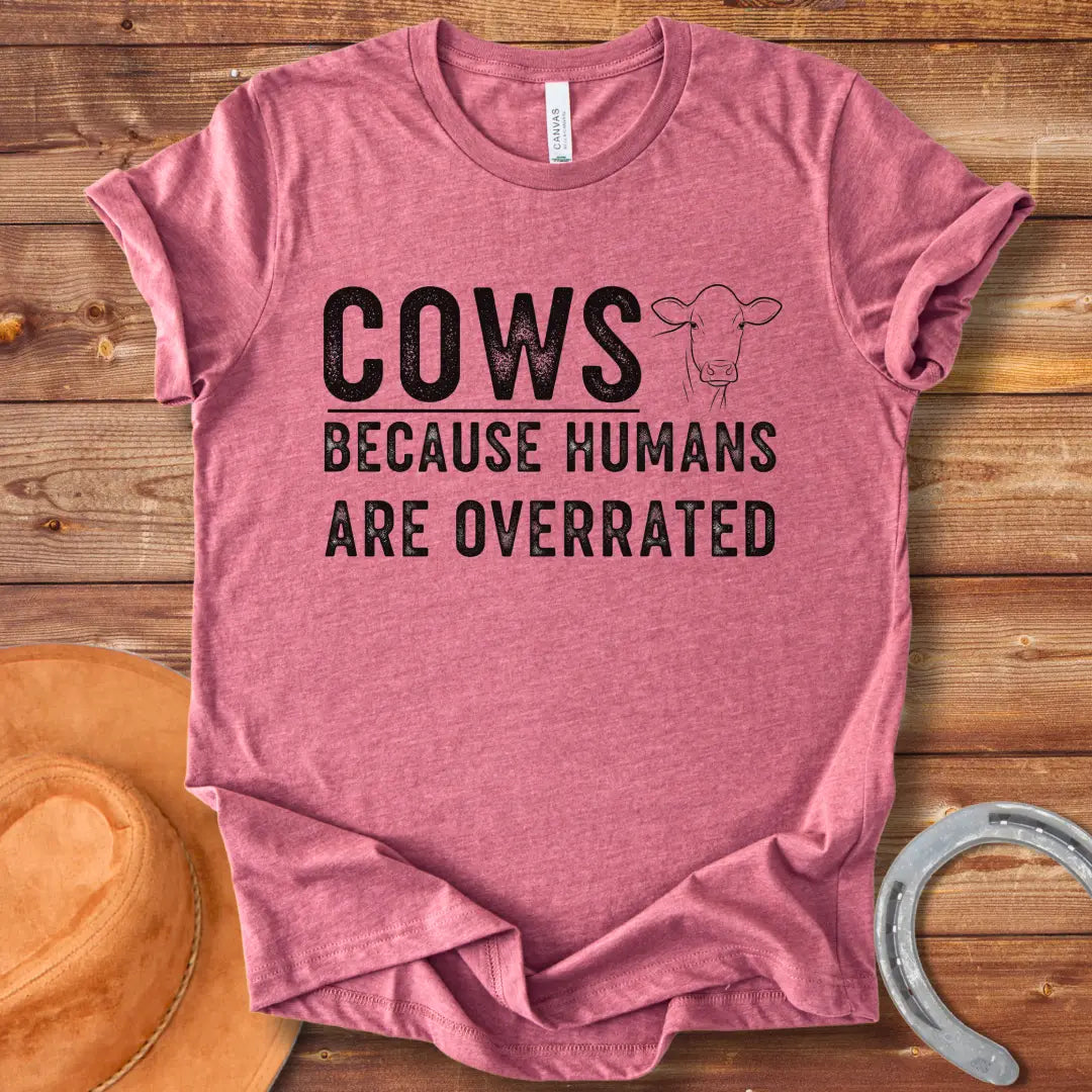 A black and white graphic t-shirt design that reads 'COWS BECAUSE HUMANS ARE OVERRATED' with a simple cow illustration.