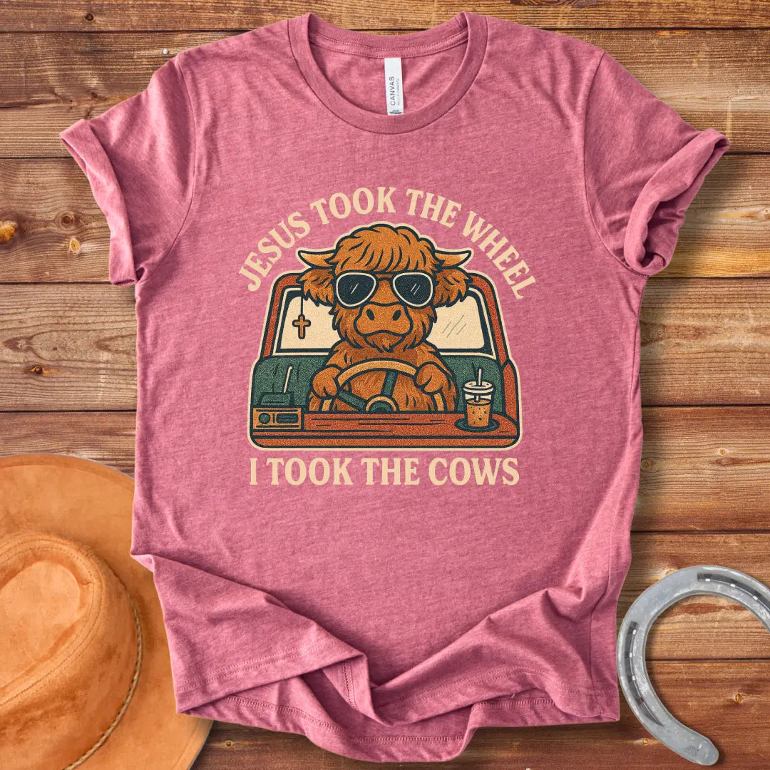 A Highland cow wearing sunglasses drives a car while holding a coffee; text reads 'Jesus took the wheel, I took the cows'.